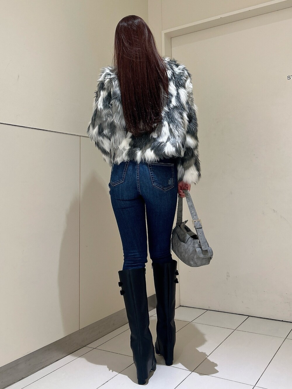 ブルー系のデニムパンツ、ブラック系のブーツ、グリーン系のショルダーバッグを着用したレディースの秋コーディネートの3枚目の写真
