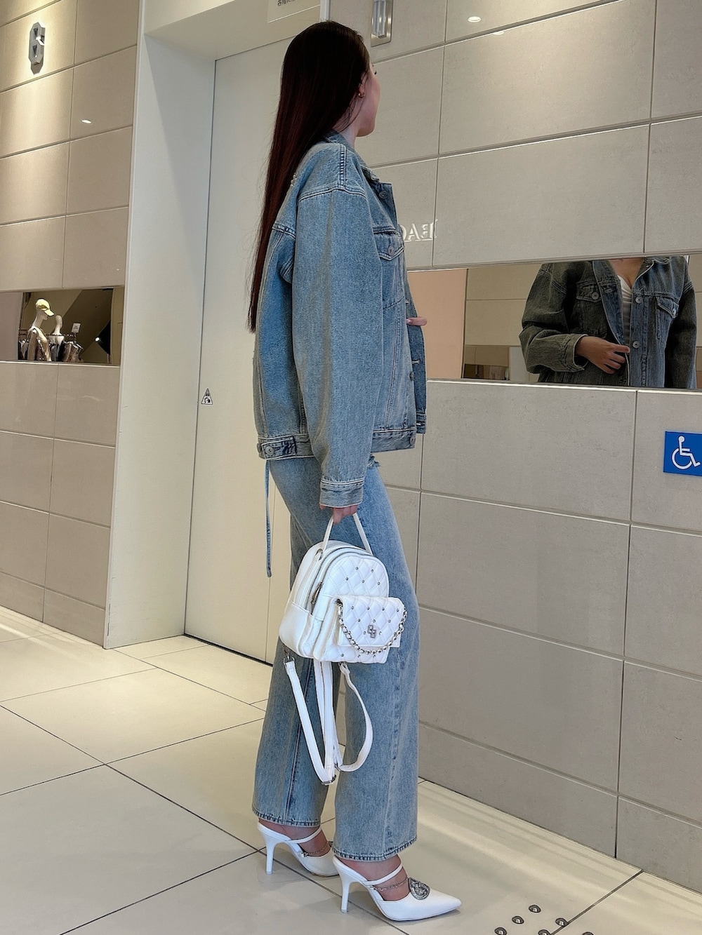 ホワイト系のパンプス、ブルー系のデニムジャケット、ホワイト系のキャミソールを着用したレディースの春コーディネートの2枚目の写真