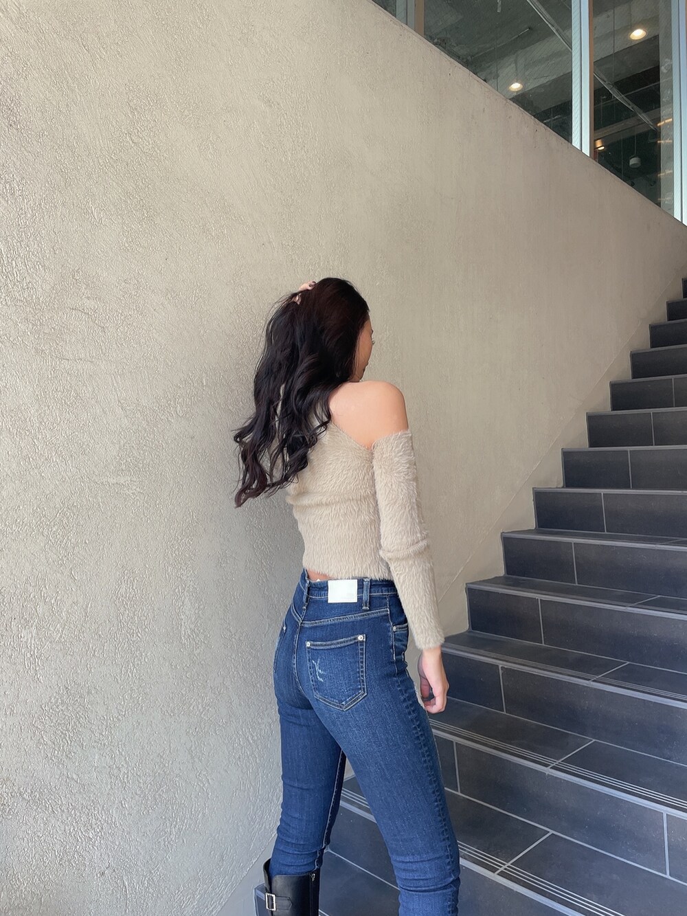 ベージュ系のニット/セーター、ブルー系のデニムパンツ、ブラック系のブーツを着用したレディースの秋コーディネートの3枚目の写真