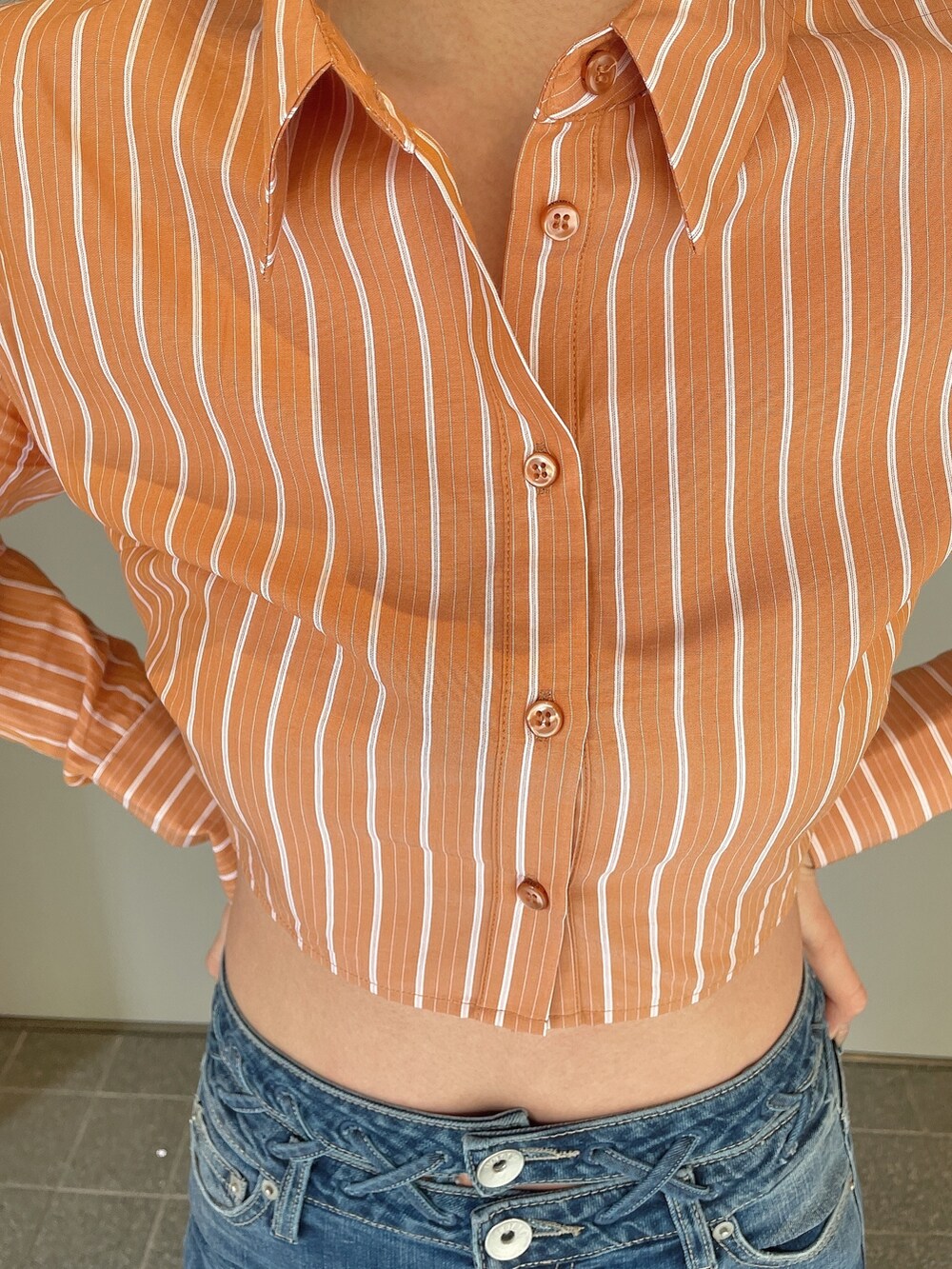 ブルー系のデニムパンツ、オレンジ系のシャツ/ブラウス、ブラック系のパンプスを着用したレディースの冬コーディネートの7枚目の写真