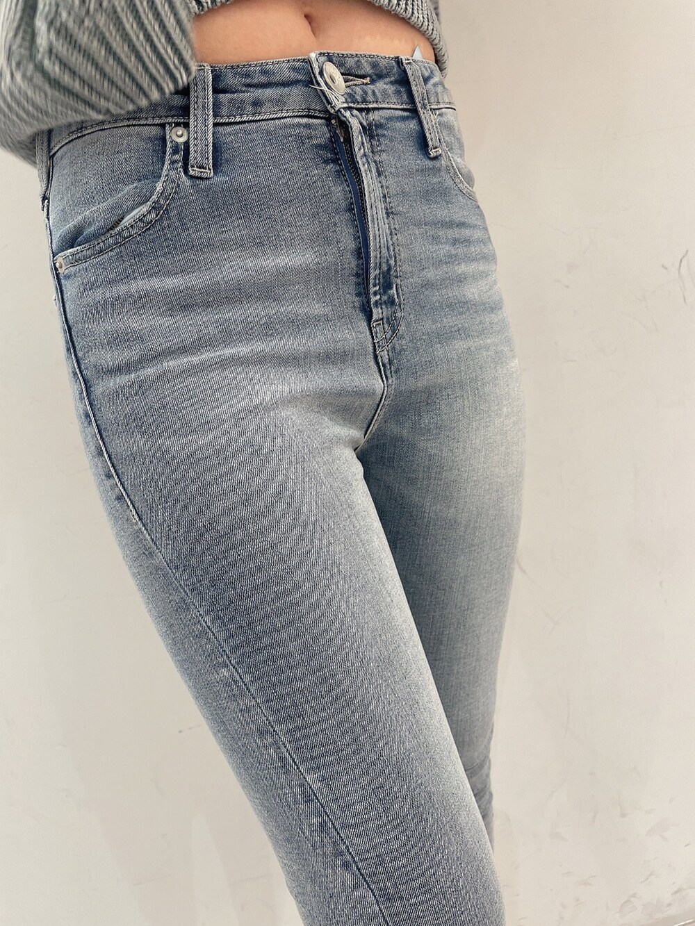 グリーン系のニット/セーター、ブルー系のデニムパンツ、ホワイト系のパンプスを着用したレディースの春コーディネートの7枚目の写真