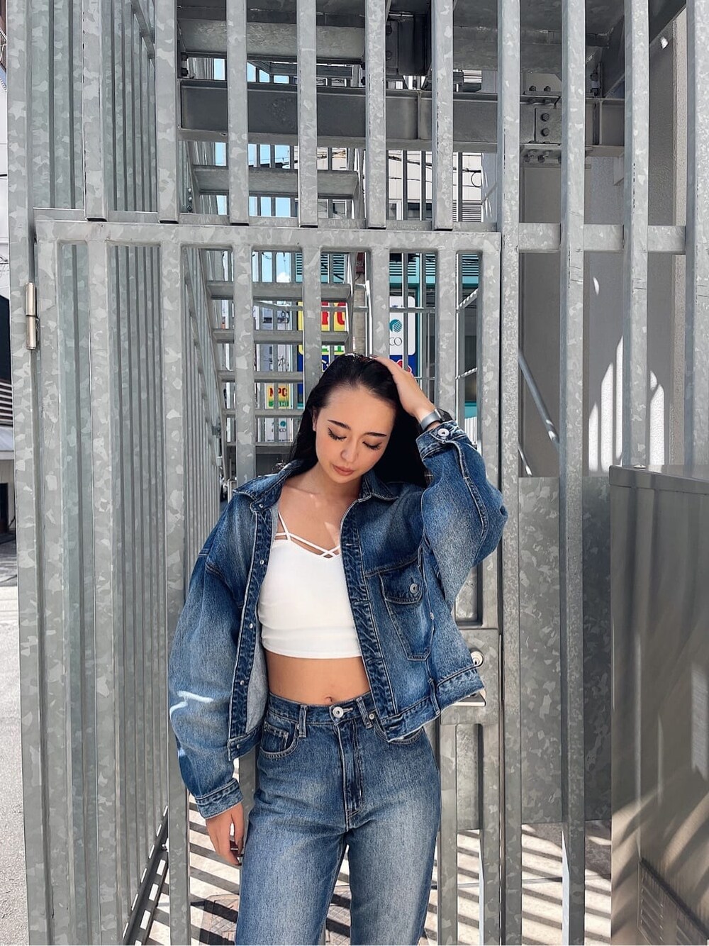 ブルー系のデニムパンツ、ブルー系のデニムジャケット、ホワイト系のキャミソールを着用したレディースの秋コーディネートの3枚目の写真