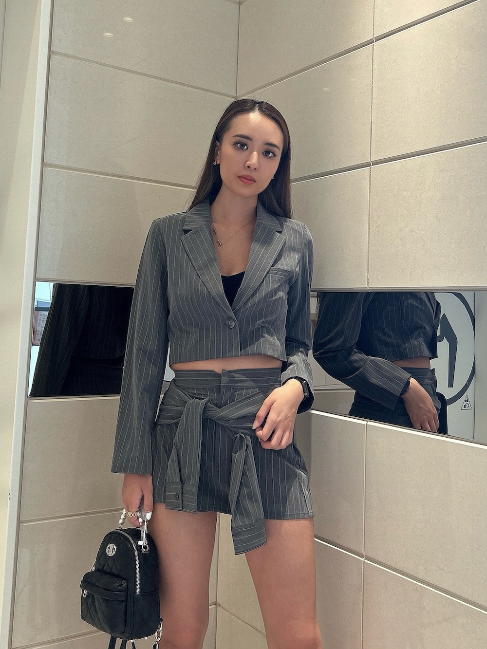 グレー系のテーラードジャケット、グレー系のスカート、ブラック系のバックパック/リュックを着用したレディースの秋コーディネートの4枚目の写真