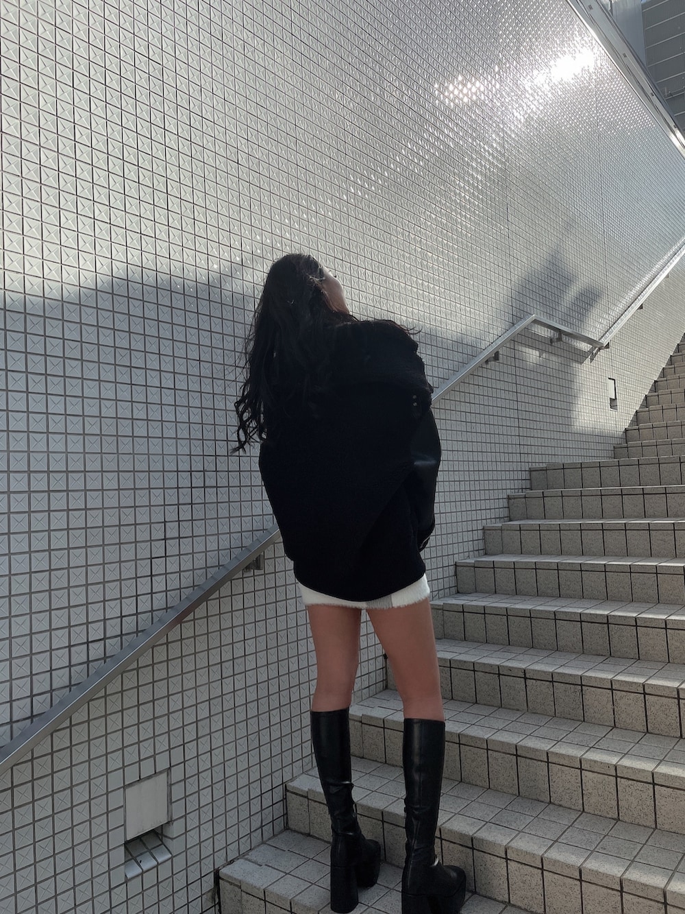 ブラック系のブルゾン、ホワイト系のワンピース、ブラック系のブーツを着用したレディースの冬コーディネートの2枚目の写真