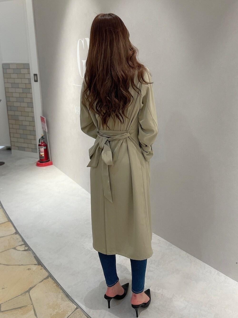 ブルー系のデニムパンツ、ホワイト系のTシャツ/カットソー、ベージュ系のトレンチコートを着用したレディースの春コーディネートの2枚目の写真