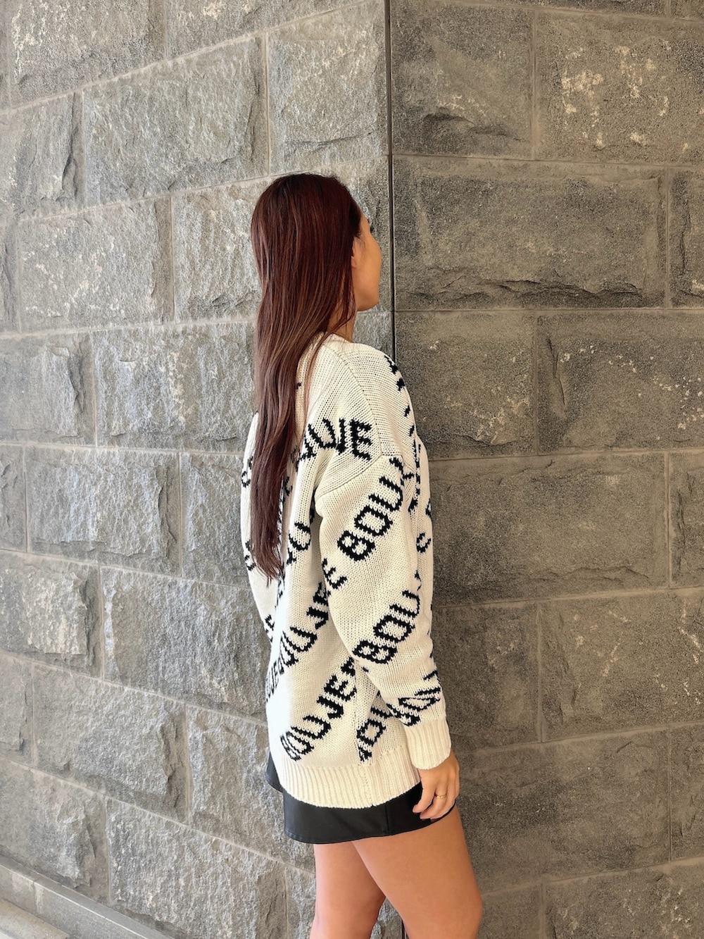 ブラック系のニット/セーター、ブラック系のスカート、ブラック系のブーツを着用したレディースの秋コーディネートの5枚目の写真