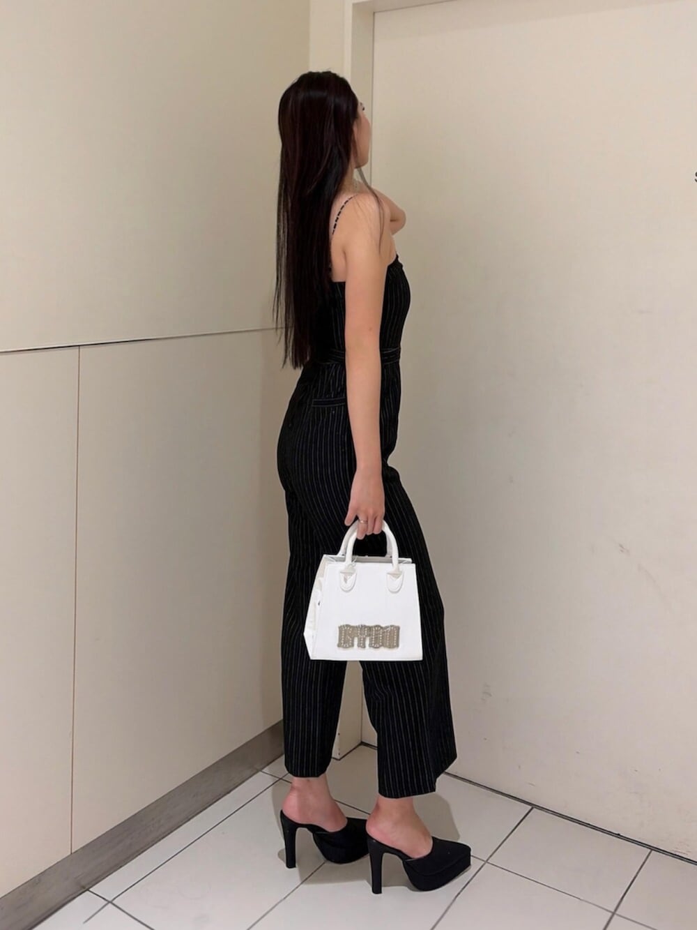 ブラック系のパンプス、ブラック系のつなぎ/オールインワン、ホワイト系のハンドバッグを着用したレディースの秋コーディネートの2枚目の写真