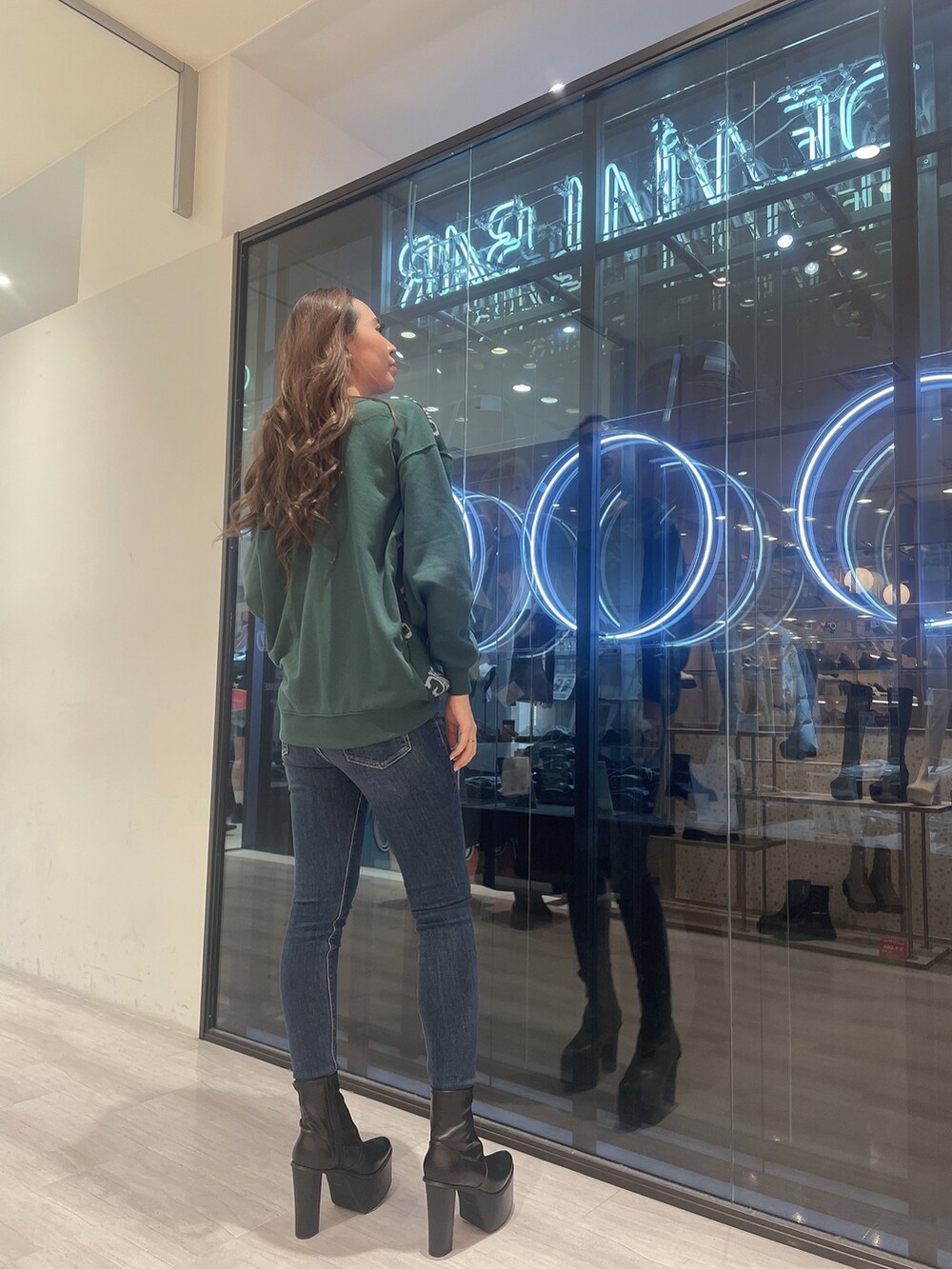 ホワイト系のTシャツ/カットソー、ブルー系のデニムパンツ、ブラック系のブーツを着用したレディースの冬コーディネートの2枚目の写真