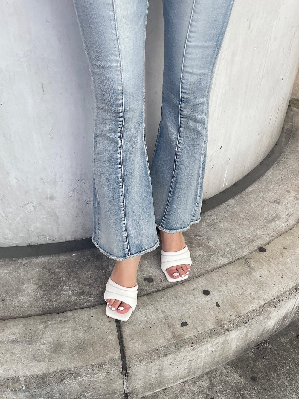 ホワイト系のニット/セーター、ホワイト系のサンダル、ブルー系のデニムパンツを着用したレディースの夏コーディネートの7枚目の写真
