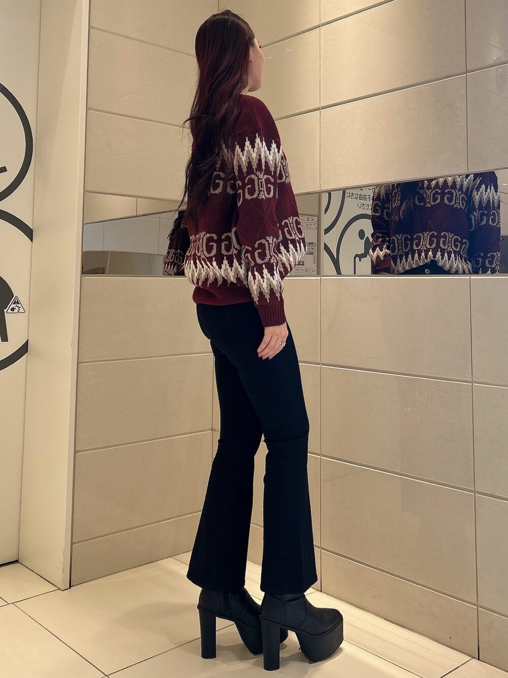 レッド系のニット/セーター、ブラック系のデニムパンツ、ブラック系のブーツを着用したレディースの冬コーディネートの2枚目の写真