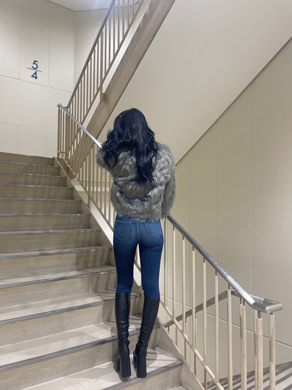 ブルー系のデニムパンツ、ホワイト系のニット/セーター、グレー系のライダースジャケットを着用したレディースの秋コーディネートの2枚目の写真