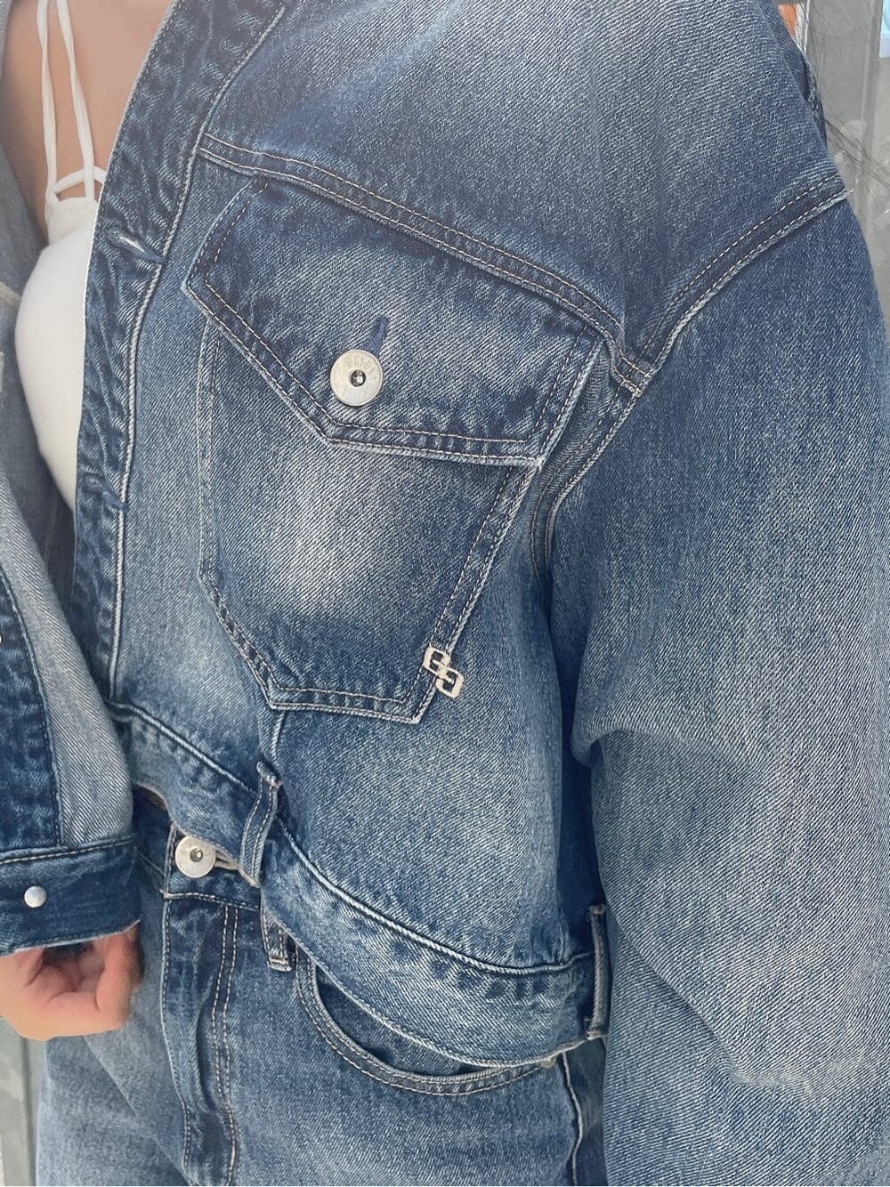 ブルー系のデニムパンツ、ブルー系のデニムジャケット、ホワイト系のキャミソールを着用したレディースの秋コーディネートの6枚目の写真