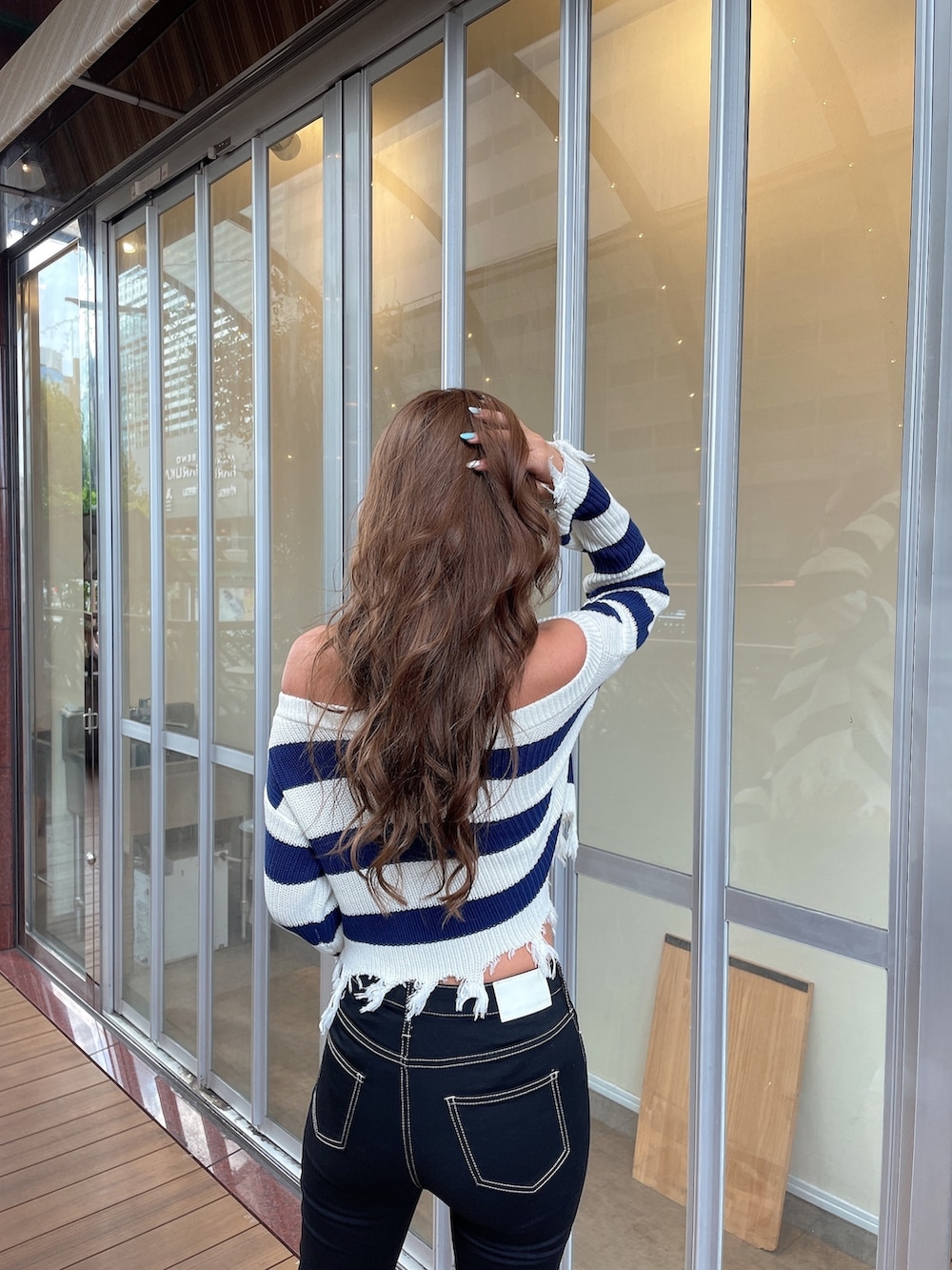 ブルー系のニット/セーター、ブルー系のデニムパンツ、ブラック系のパンプスを着用したレディースの夏コーディネートの4枚目の写真