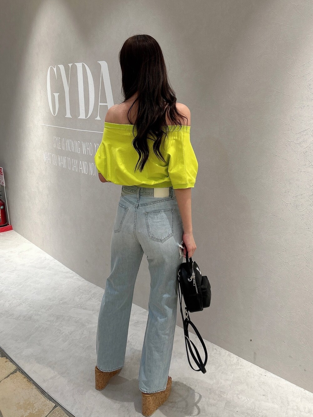 イエロー系のTシャツ/カットソー、ブルー系のデニムパンツ、ベージュ系のサンダルを着用したレディースの春コーディネートの3枚目の写真