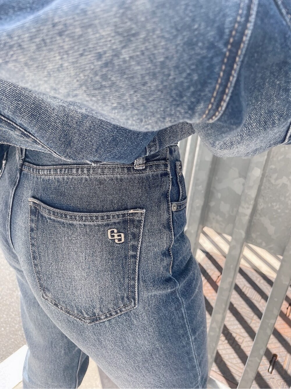 ブルー系のデニムパンツ、ブルー系のデニムジャケット、ホワイト系のキャミソールを着用したレディースの秋コーディネートの7枚目の写真