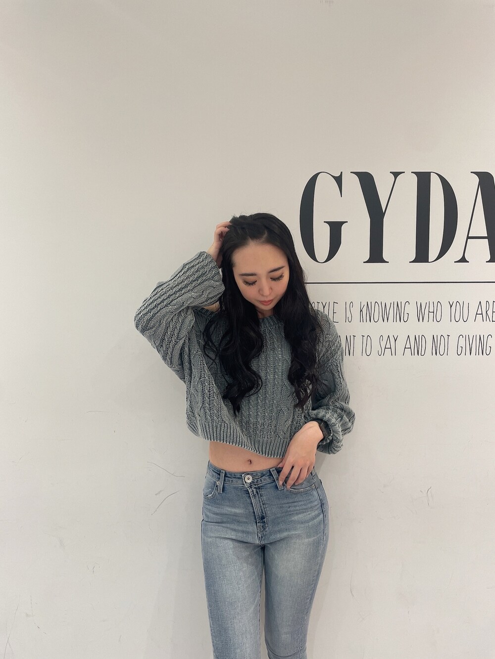 グリーン系のニット/セーター、ブルー系のデニムパンツ、ホワイト系のパンプスを着用したレディースの春コーディネートの4枚目の写真