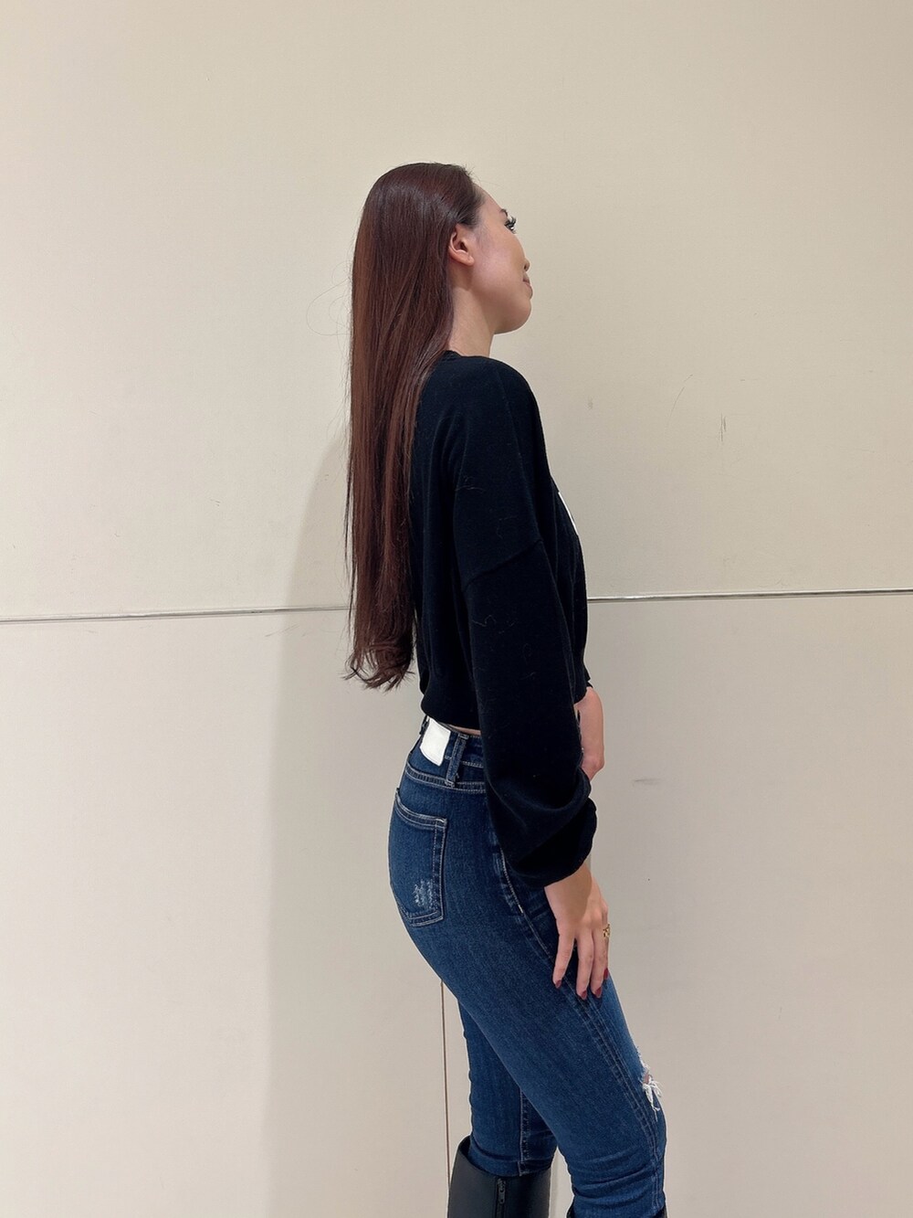 ブラック系のニット/セーター、ブラック系のブーツ、ブルー系のデニムパンツを着用したレディースの秋コーディネートの5枚目の写真