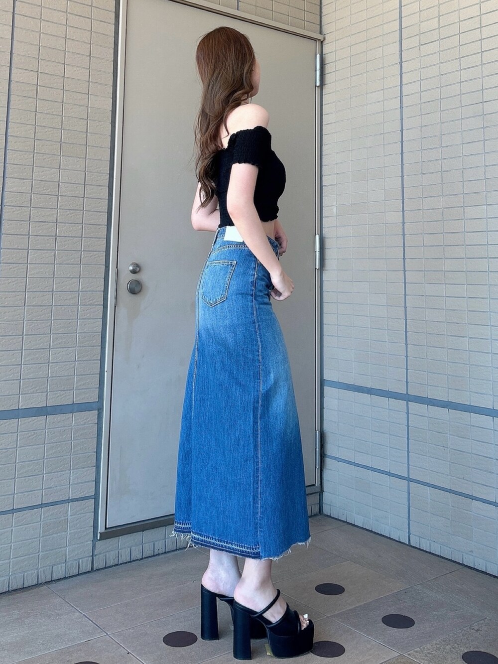 ブラック系のサンダル、ブルー系のデニムスカート、ブラック系のTシャツ/カットソーを着用したレディースの夏コーディネートの2枚目の写真