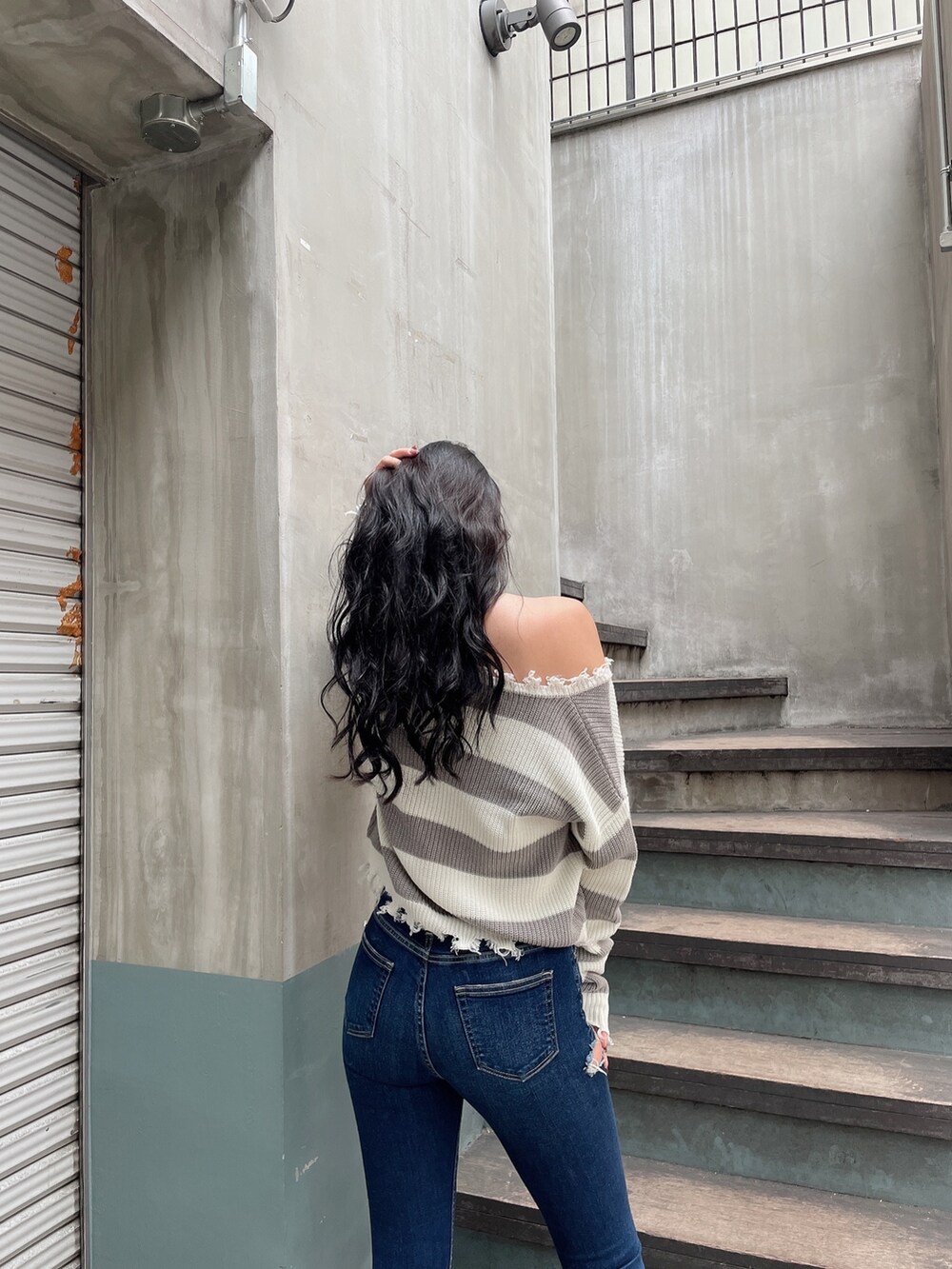 ブルー系のデニムパンツ、ブラック系のパンプス、グレー系のニット/セーターを着用したレディースの冬コーディネートの2枚目の写真