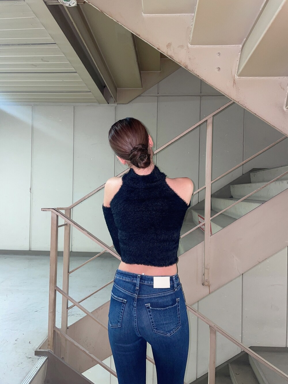 ブルー系のデニムパンツ、ブラック系のニット/セーター、ブラック系のパンプスを着用したレディースの秋コーディネートの4枚目の写真