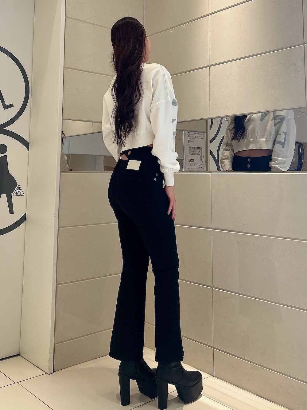 ホワイト系のニット/セーター、ブラック系のデニムパンツ、ブラック系のブーツを着用したレディースの冬コーディネートの2枚目の写真