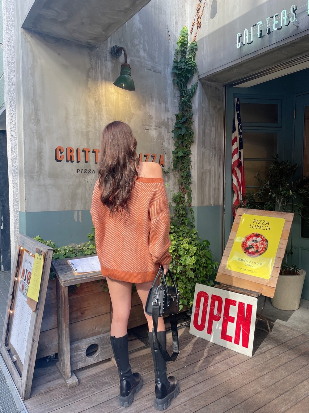 ブルー系のデニムスカート、ブラック系のボストンバッグ、オレンジ系のニット/セーターを着用したレディースの秋コーディネートの3枚目の写真