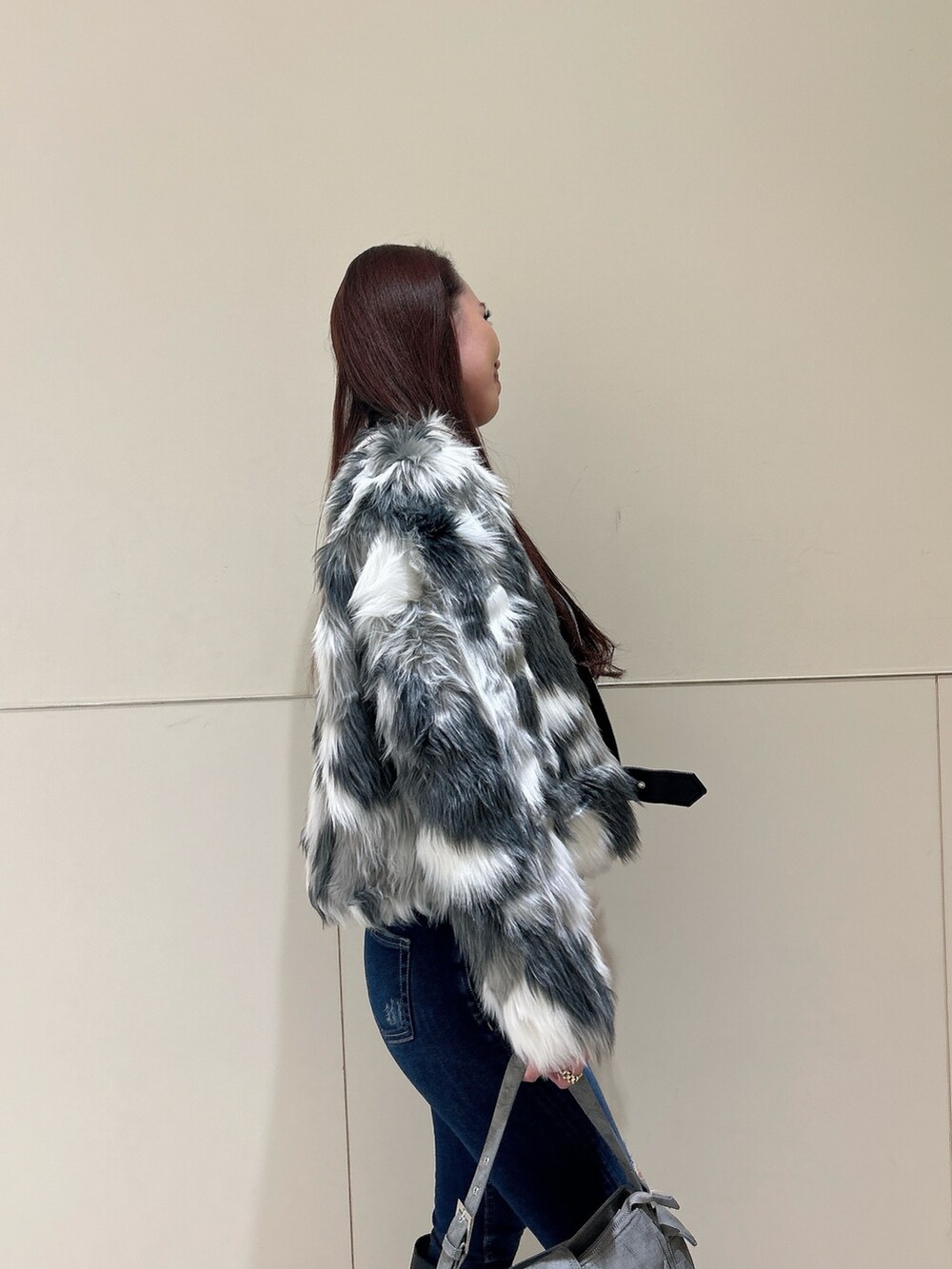 ブルー系のデニムパンツ、ブラック系のブーツ、グリーン系のショルダーバッグを着用したレディースの秋コーディネートの5枚目の写真