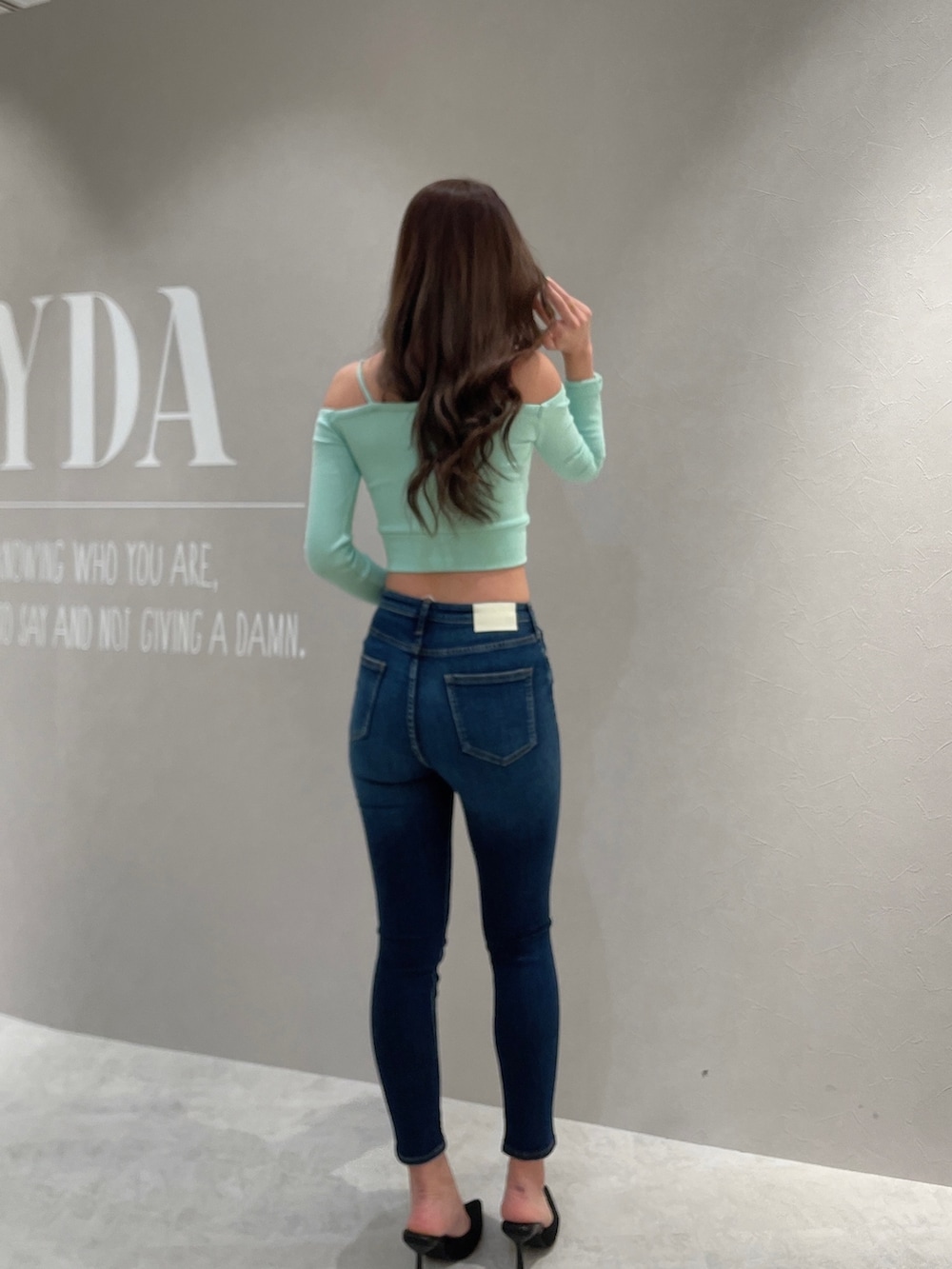 グリーン系のTシャツ/カットソー、ブルー系のデニムパンツ、ブラック系のパンプスを着用したレディースの春コーディネートの2枚目の写真