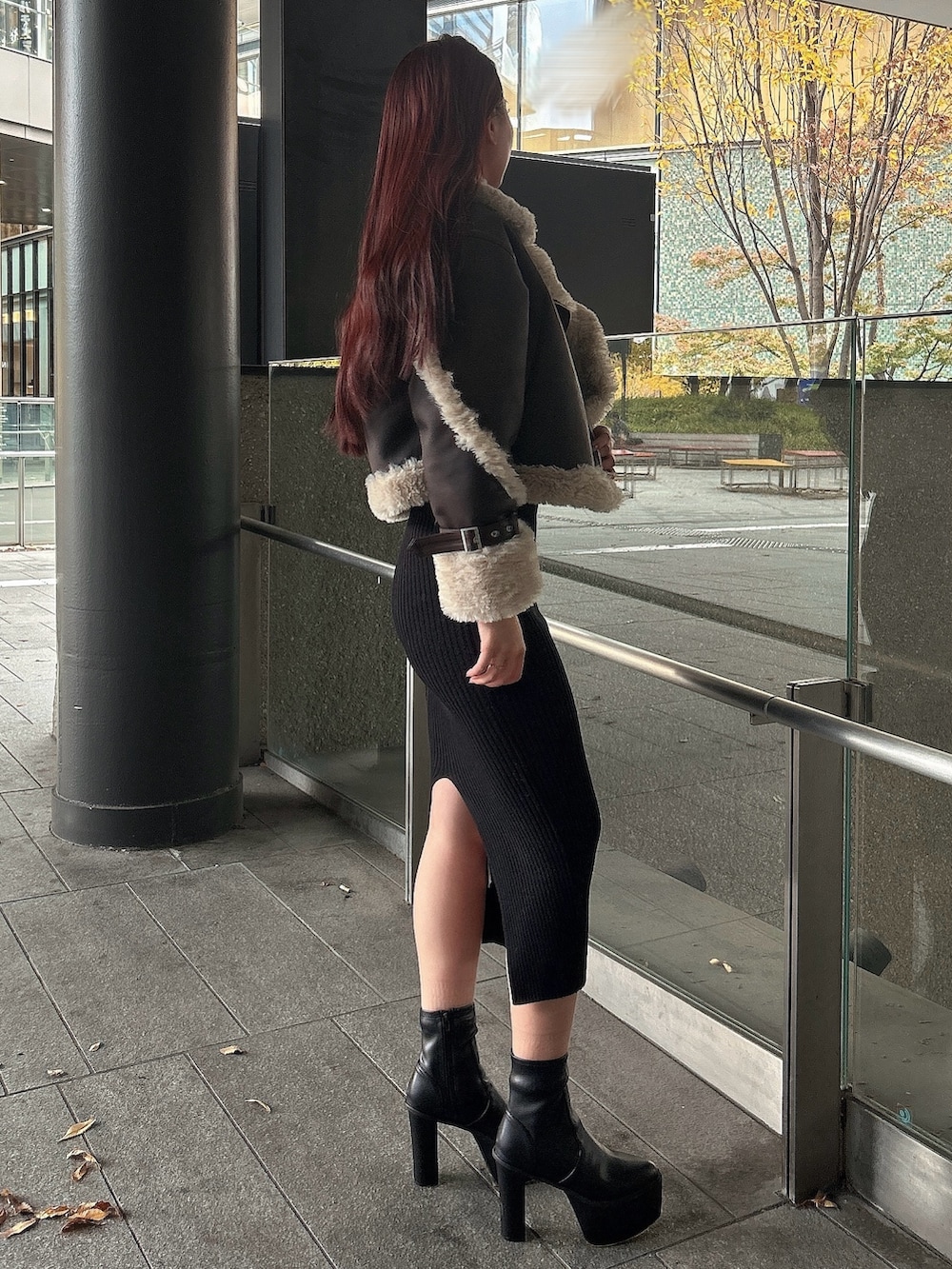 ブラウン系のムートンコート、ブラック系のブーツを着用したレディースの秋コーディネートの2枚目の写真