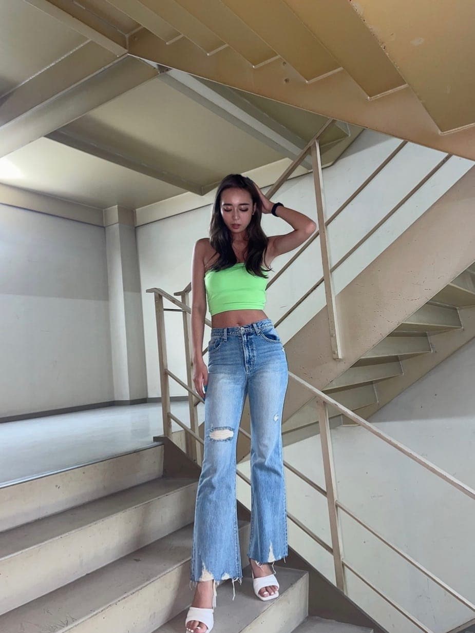 ホワイト系のサンダル、ブルー系のデニムパンツ、グリーン系のチューブトップを着用したレディースの夏コーディネートの5枚目の写真