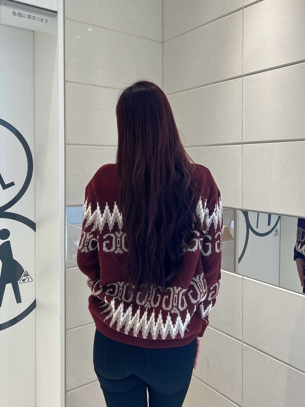 レッド系のニット/セーター、ブラック系のデニムパンツ、ブラック系のブーツを着用したレディースの冬コーディネートの6枚目の写真