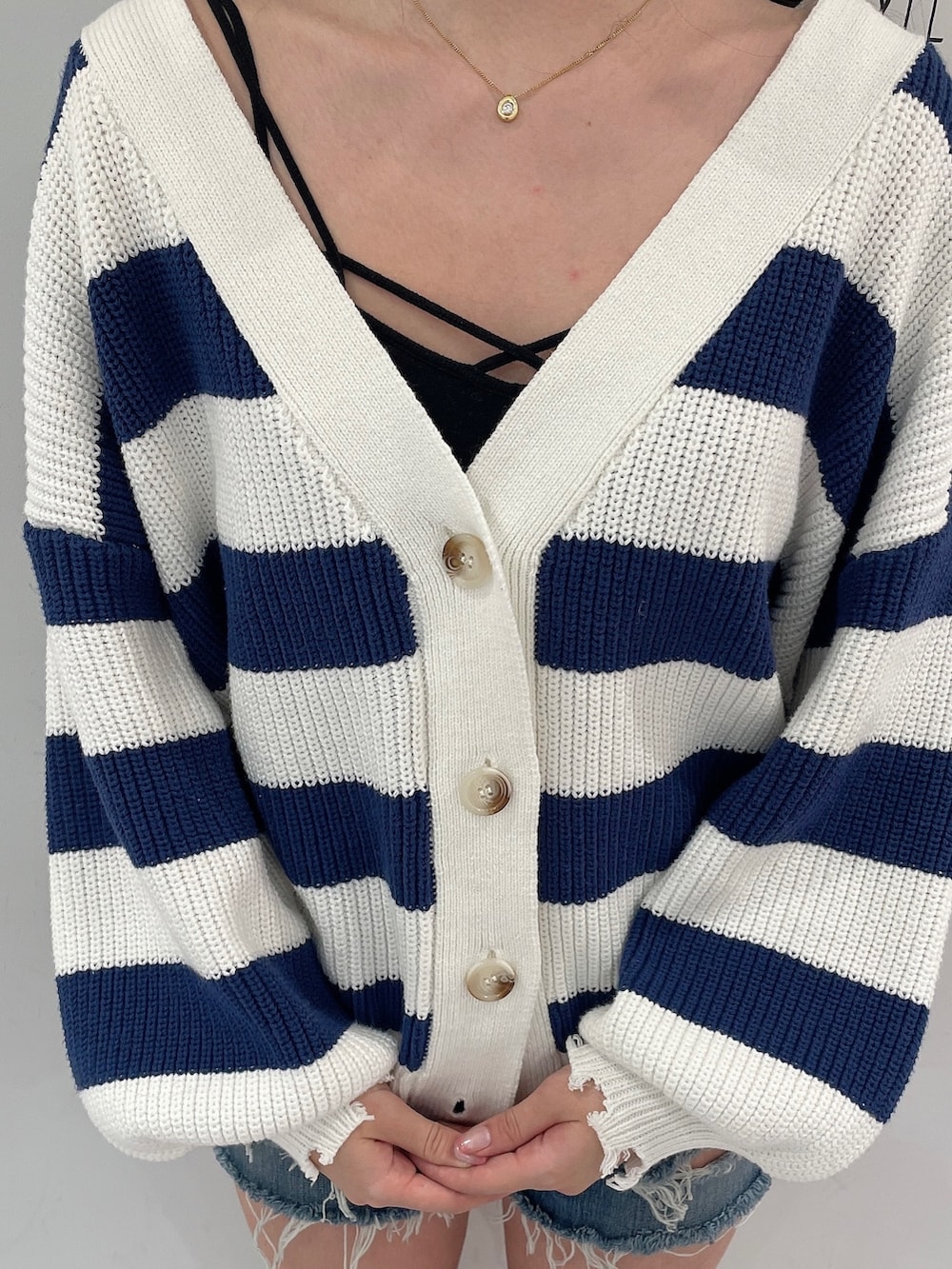 ブルー系のデニムパンツ、ブルー系のカーディガン/ボレロ、ブラック系のキャミソールを着用したレディースの春コーディネートの6枚目の写真