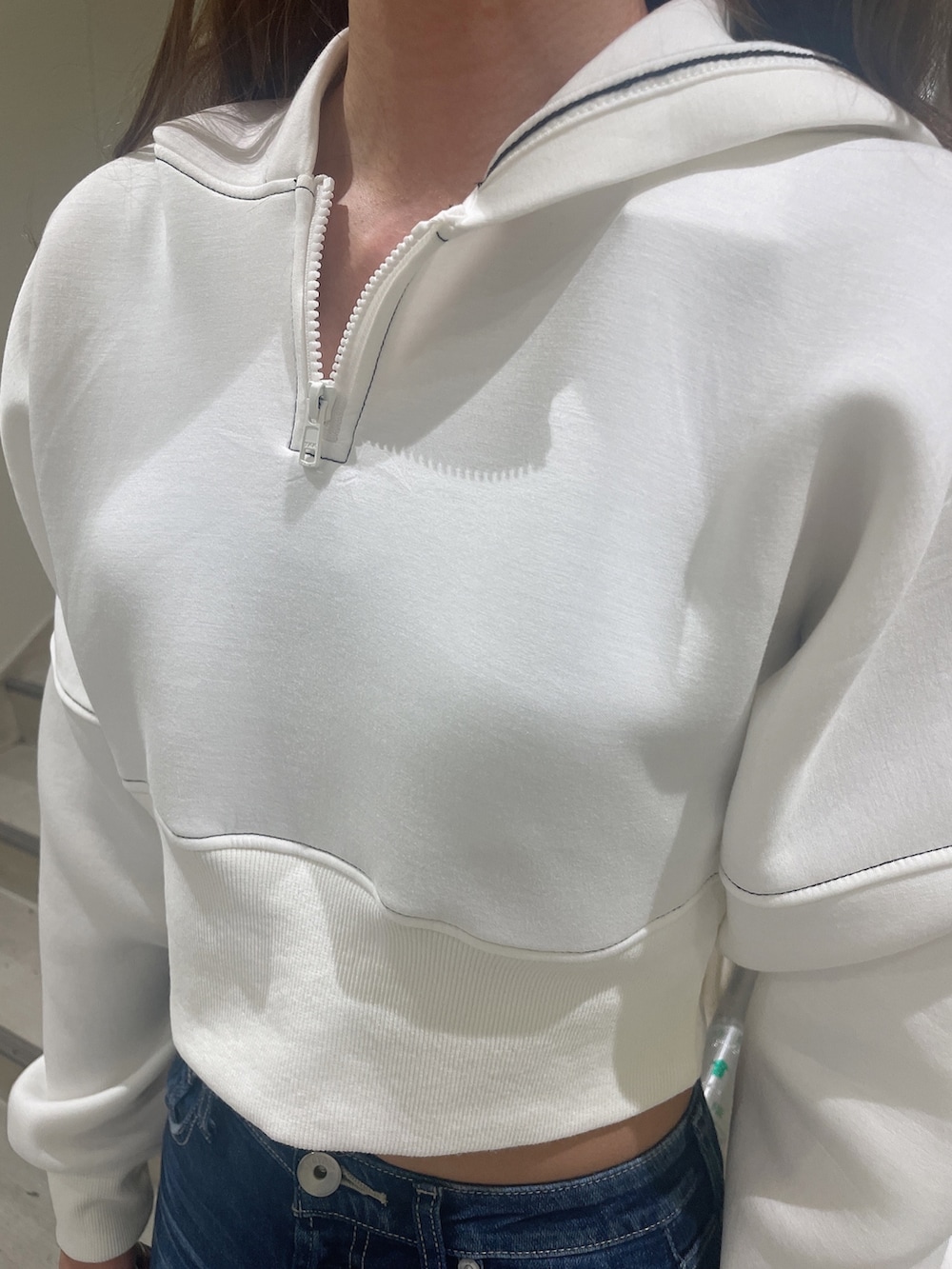 ブラック系のブーツ、ホワイト系のパーカー、ブルー系のデニムパンツを着用したレディースの秋コーディネートの5枚目の写真