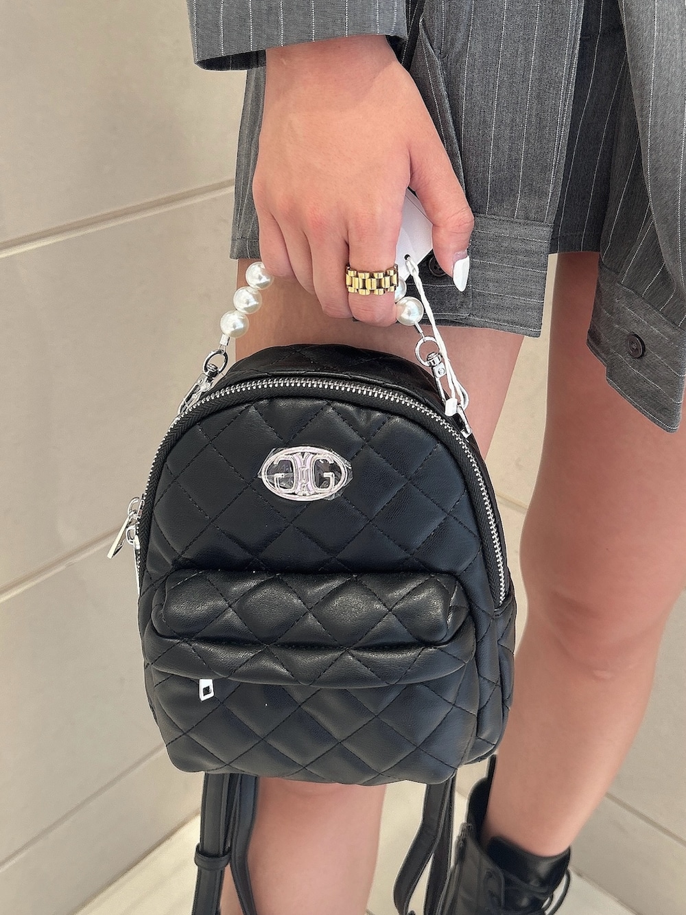 グレー系のテーラードジャケット、グレー系のスカート、ブラック系のバックパック/リュックを着用したレディースの秋コーディネートの7枚目の写真