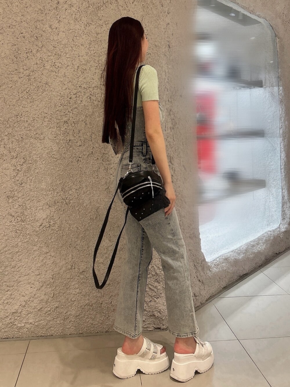 グリーン系のニット/セーター、ブルー系のつなぎ/オールインワン、ブラック系のバックパック/リュックを着用したレディースの春コーディネートの2枚目の写真