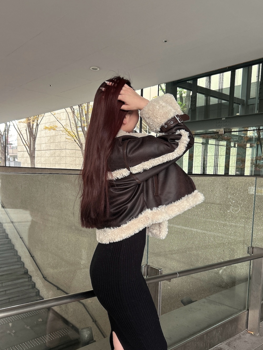 ブラウン系のムートンコート、ブラック系のブーツを着用したレディースの秋コーディネートの5枚目の写真