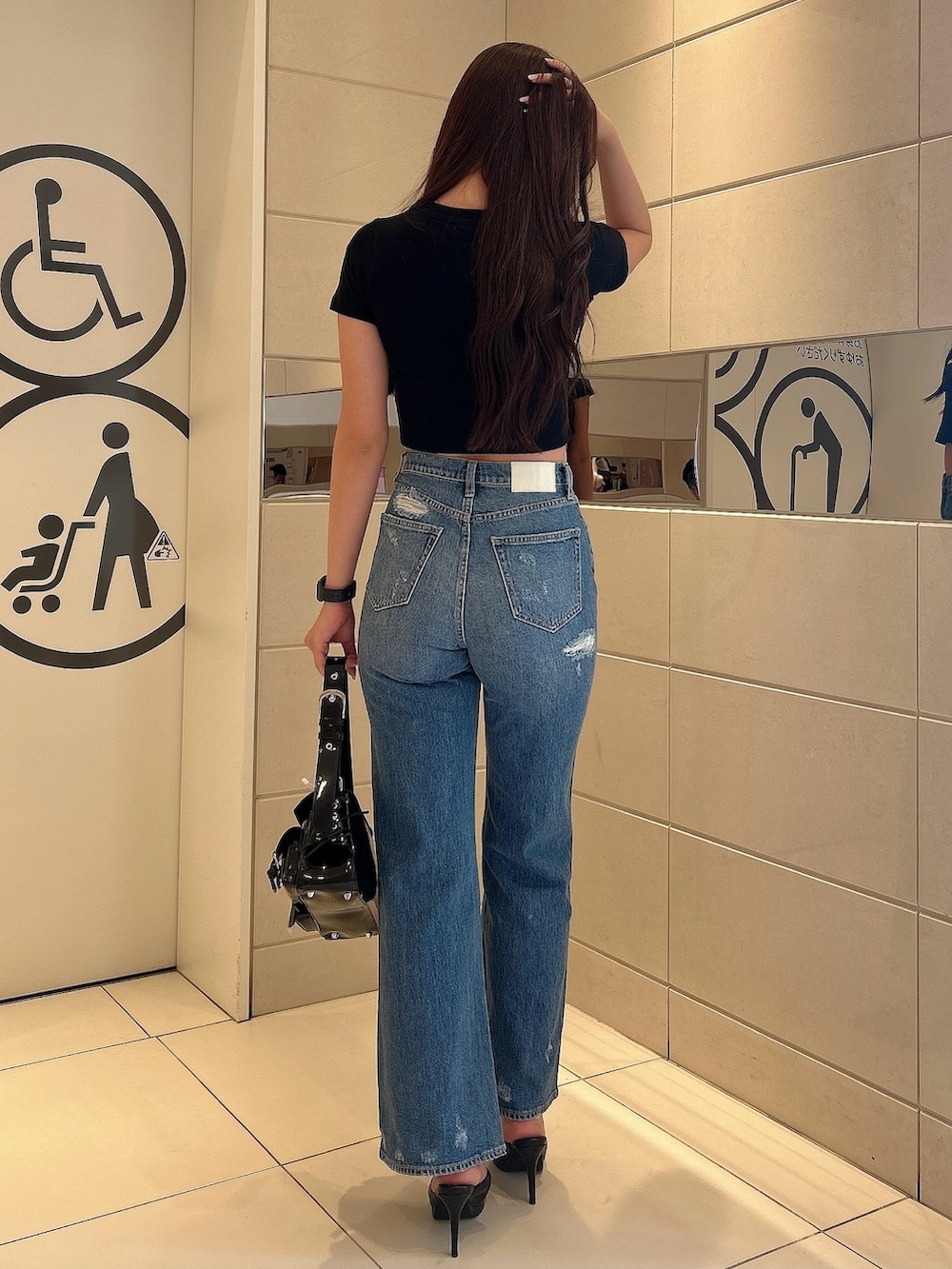 ブラック系のTシャツ/カットソー、ブルー系のデニムパンツ、ブラック系のハンドバッグを着用したレディースの春コーディネートの3枚目の写真