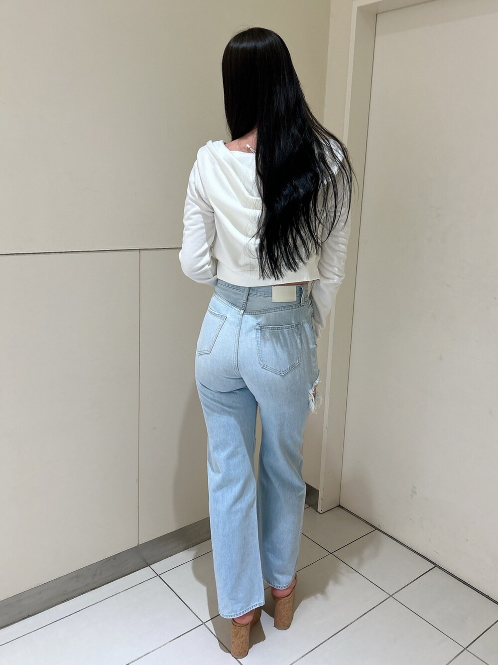 ホワイト系のパーカー、ブルー系のデニムパンツ、ホワイト系のチューブトップを着用したレディースの春コーディネートの3枚目の写真