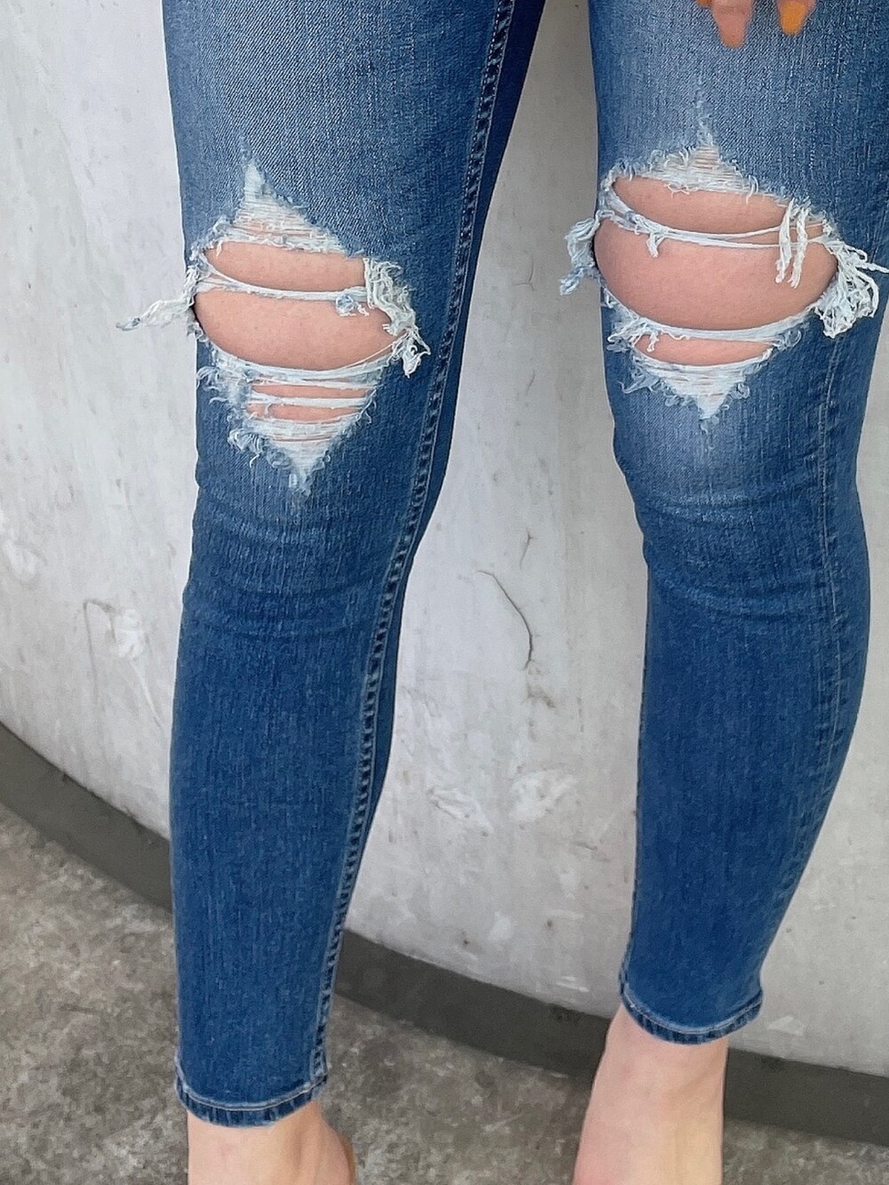 オレンジ系のニット/セーター、ブルー系のデニムパンツ、ベージュ系のサンダルを着用したレディースの春コーディネートの6枚目の写真