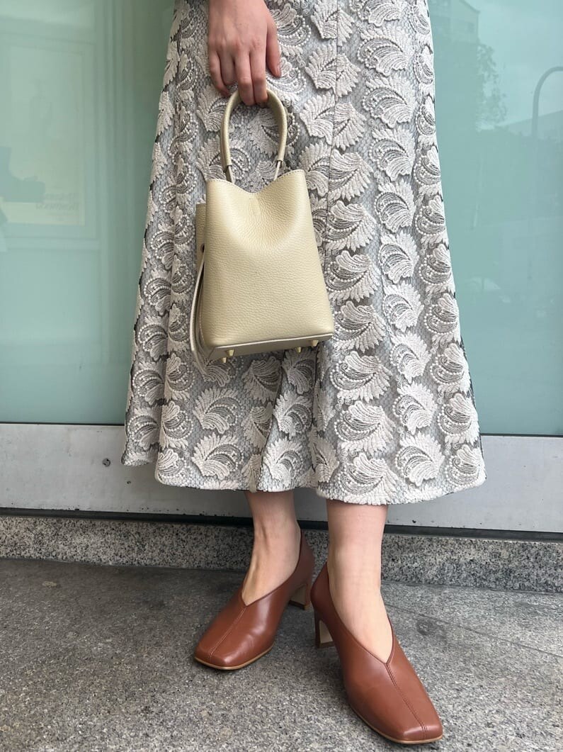 ホワイト系のハンドバッグ、ホワイト系のパンプス、グリーン系のシャツ/ブラウスを着用したレディースの春コーディネートの6枚目の写真