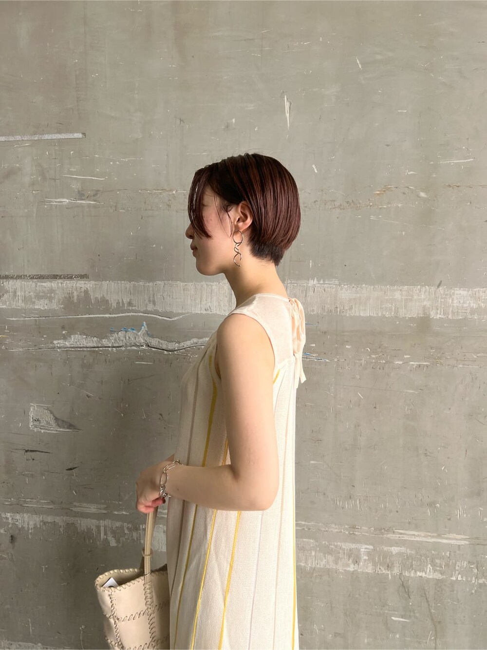 イエロー系のサンダル、イエロー系のワンピース、シルバー系のピアス（両耳用）を着用したレディースの夏コーディネートの6枚目の写真