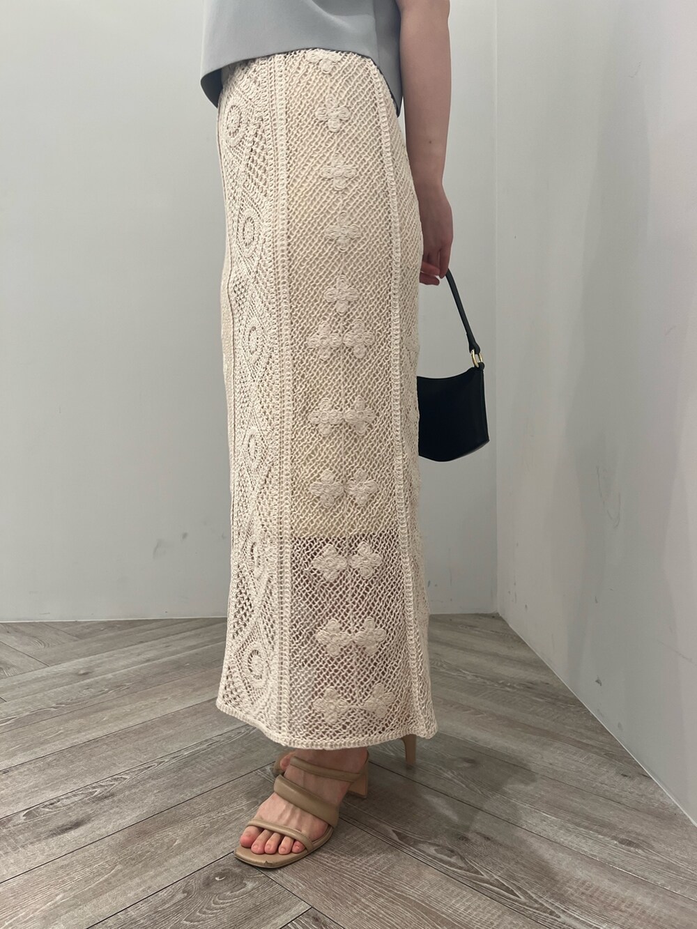 ベージュ系のサンダル、ブラック系のハンドバッグ、ブルー系のニット/セーターを着用したレディースの春コーディネートの7枚目の写真