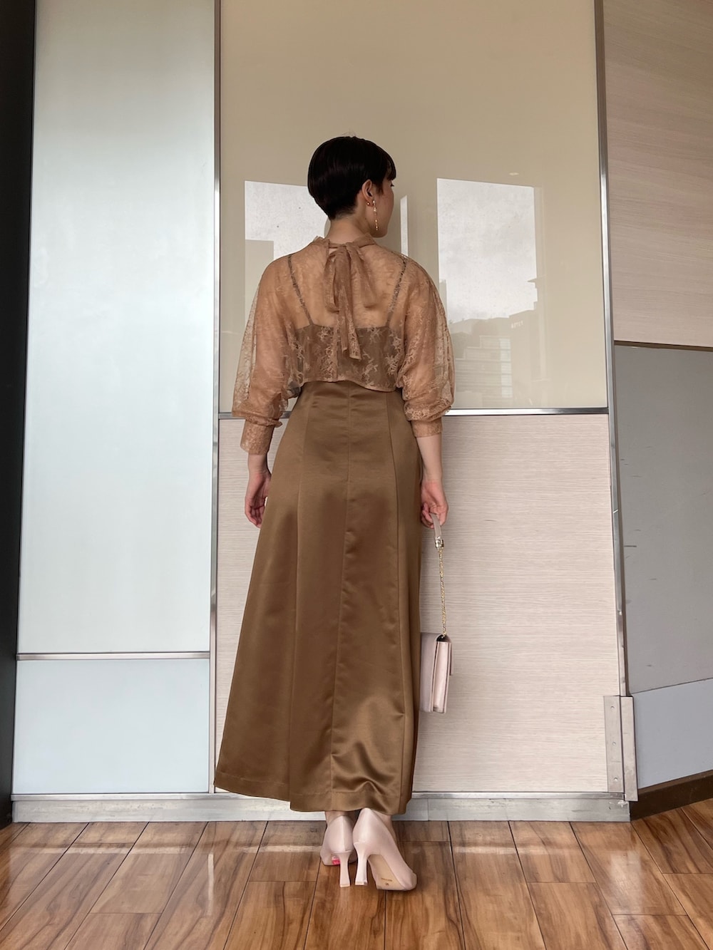 ベージュ系のクラッチバッグ、ブラウン系のドレス、ベージュ系のパンプスを着用したレディースの夏コーディネートの2枚目の写真