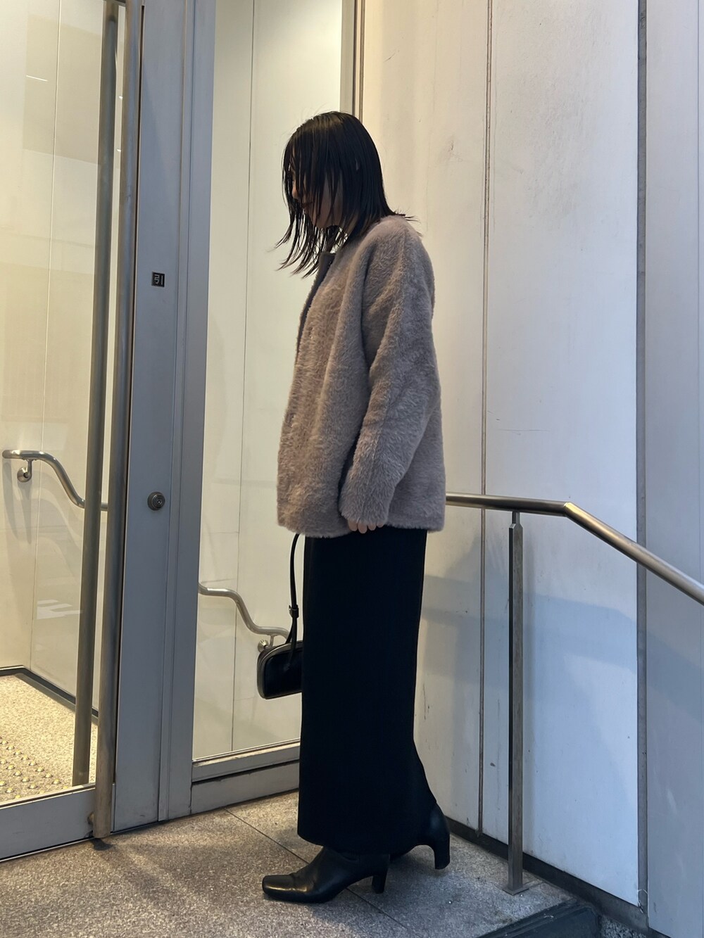 ブラック系のワンピース、ブラウン系のカーディガン/ボレロ、ブラック系のブーツを着用したレディースの冬コーディネートの2枚目の写真