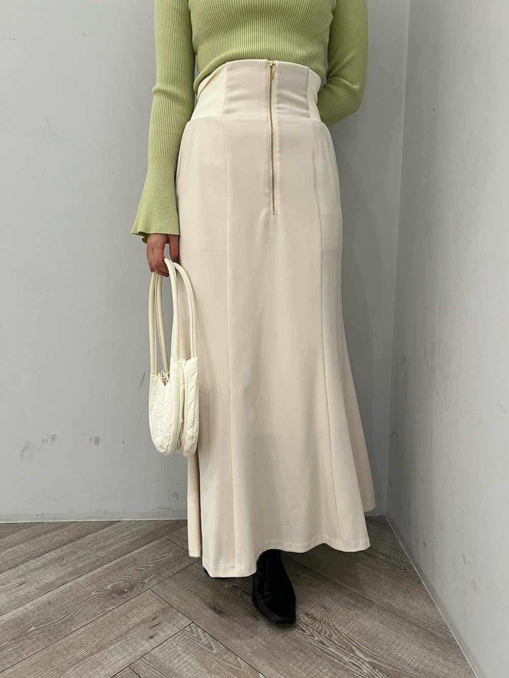 グリーン系のニット/セーター、ホワイト系のスカートを着用したレディースの冬コーディネートの8枚目の写真