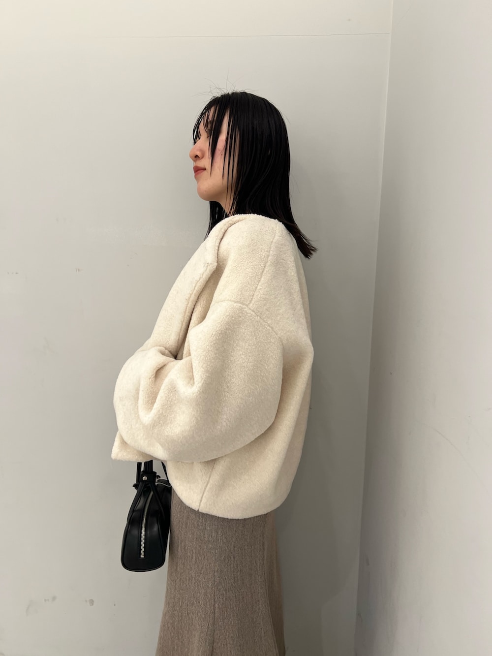 ホワイト系のブルゾン、ベージュ系のジャンパースカート、ブラック系のニット/セーターを着用したレディースの冬コーディネートの5枚目の写真