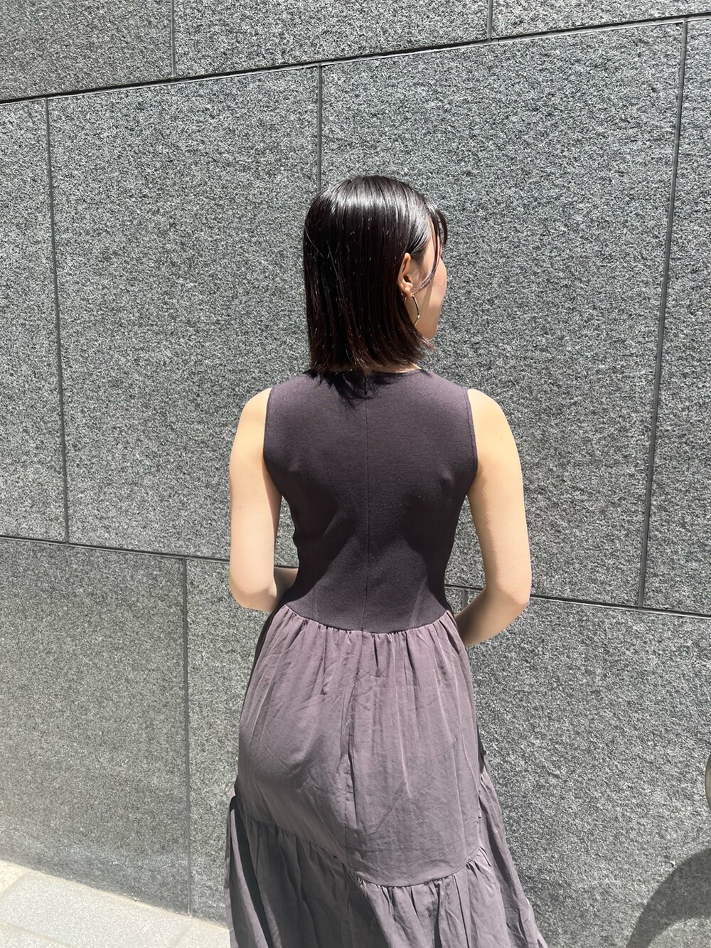 ブラック系のショルダーバッグ、ブラック系のサンダル、グレー系のワンピースを着用したレディースの春コーディネートの5枚目の写真