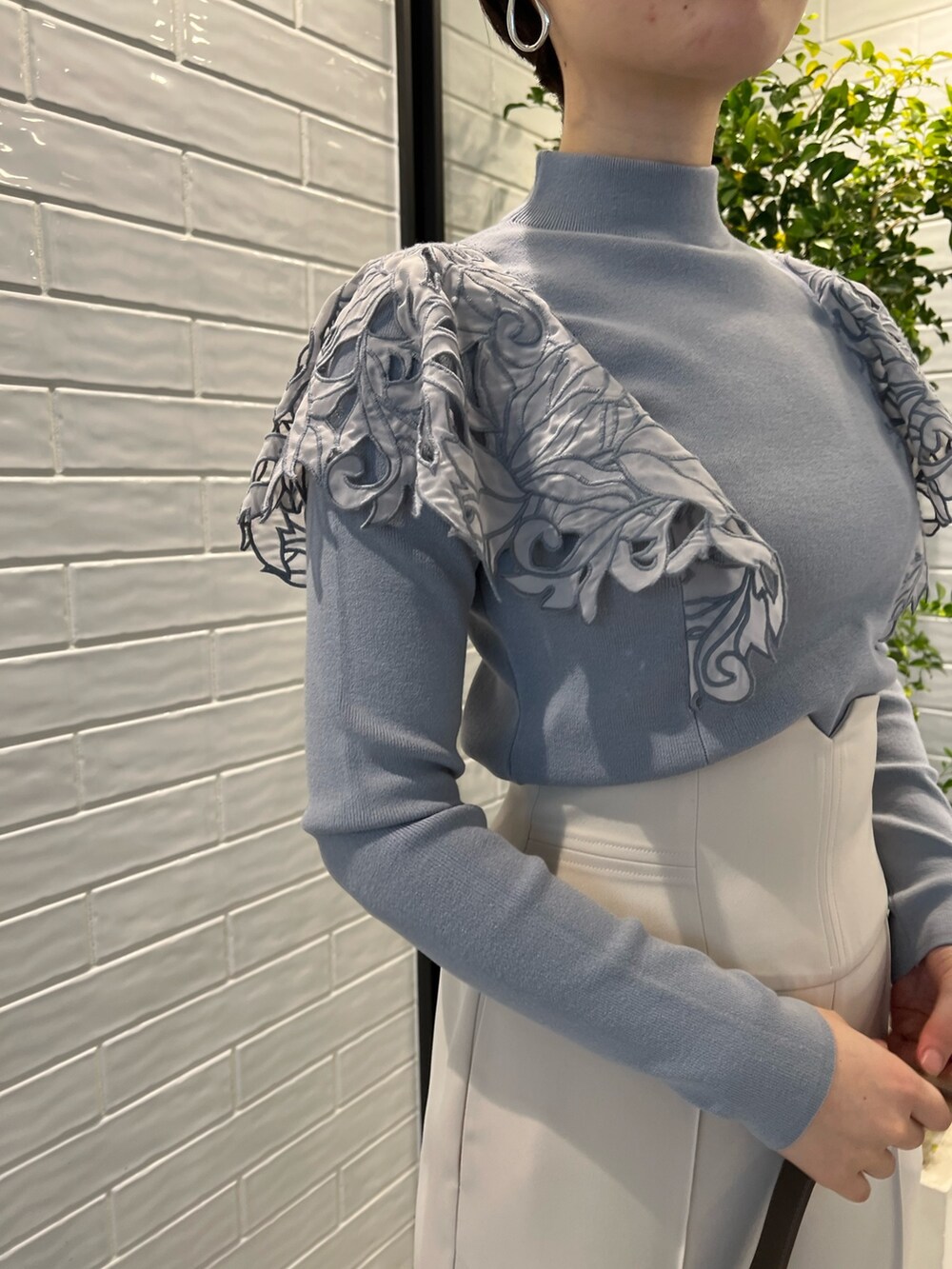 ベージュ系のノーカラーコート、ベージュ系のショルダーバッグ、レッド系のブーツを着用したレディースの冬コーディネートの8枚目の写真