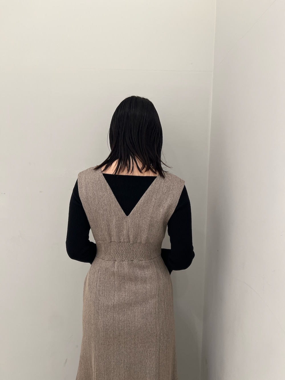 ホワイト系のブルゾン、ベージュ系のジャンパースカート、ブラック系のニット/セーターを着用したレディースの冬コーディネートの9枚目の写真