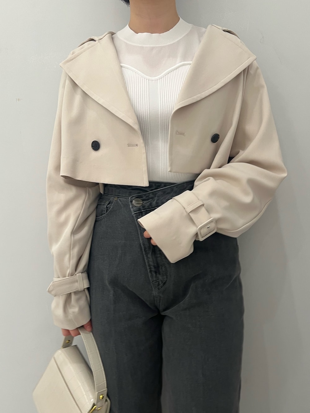 ホワイト系のトレンチコート、ホワイト系のニット/セーター、ブラック系のデニムパンツを着用したレディースの冬コーディネートの5枚目の写真